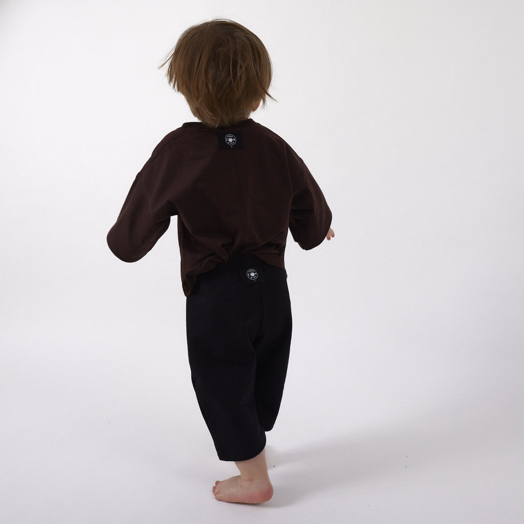 Peque de 2 años de espalda con la Polera Ternura y el Pantalón Pantera talla 1, con las etiquetas por fuera