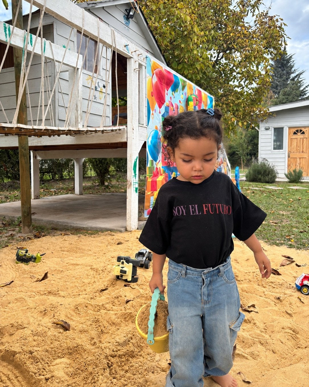 Elo&iacute;sa (3 a&ntilde;os) con Polera Futuro talla 2, jugando con un balde en el arenero