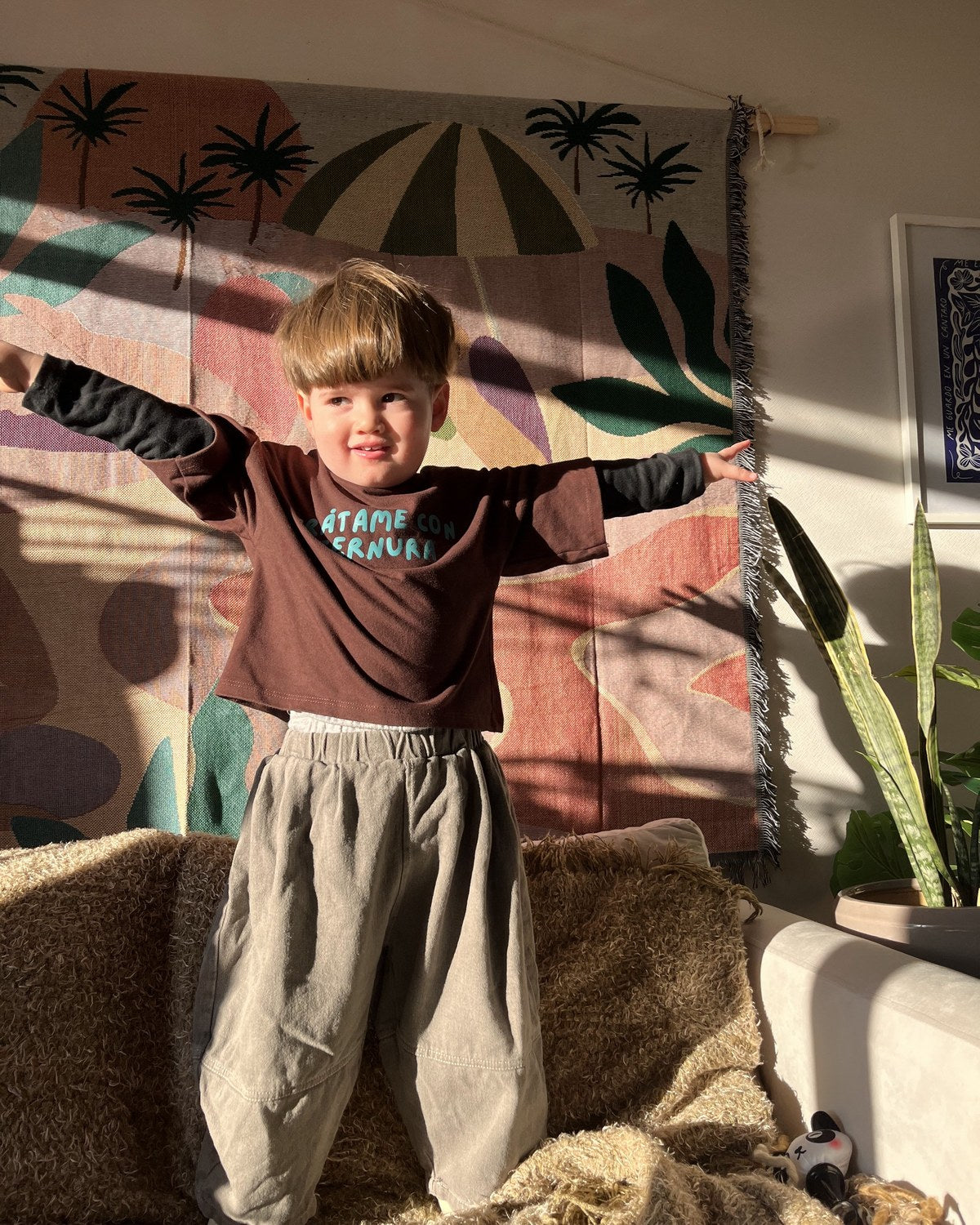 Ren (casi 3 a&ntilde;os) con los brazos abiertos, con Polera Ternura talla 2 sobre una capa negra de manga larga