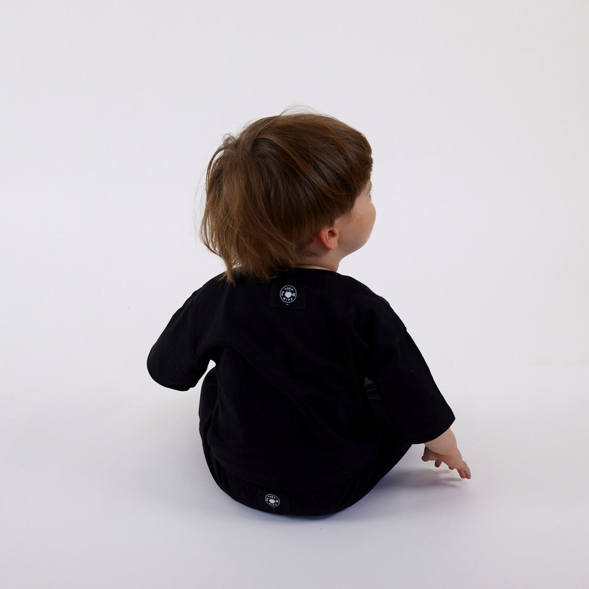 Polera Futuro y Short Dinosaurio vistos de espalda, con las etiquetas por fuera
