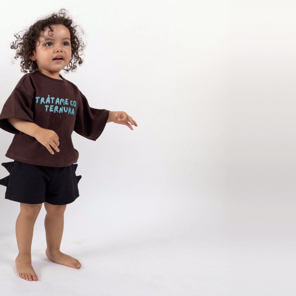 Peque de 2 años en movimiento con la Polera Ternura café oscuro talla 2 y short negro con cuernos de dinosaurio