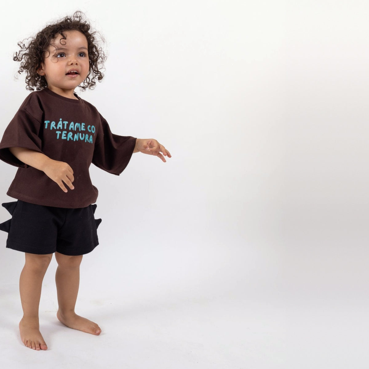 Peque de 2 años en movimiento con la Polera Ternura café oscuro talla 2 y short negro con cuernos de dinosaurio