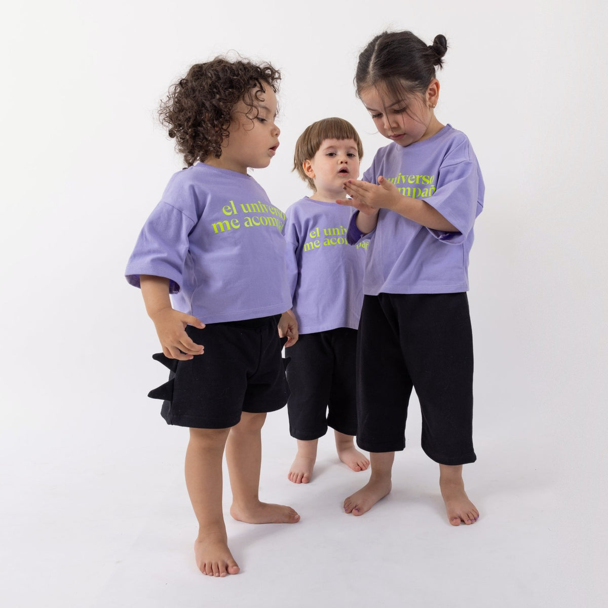 Tres peques usando la Polera Universo en distintas tallas: una de 2 años con talla 1, otra de 2 años con talla 2 y una de 3 años con talla 2