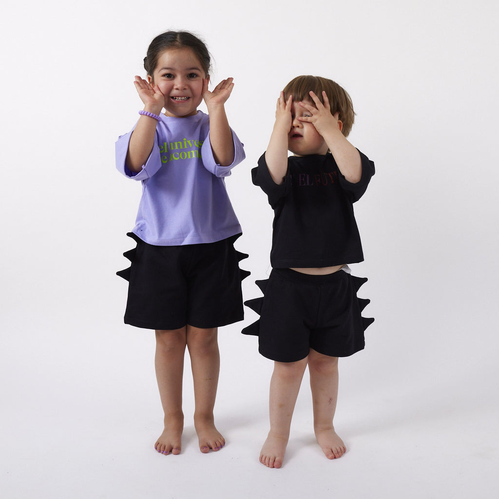 Dos peques usando el Short Dinosaurio negro: una de 3 años con talla 2 y otro de 2 años con talla 1