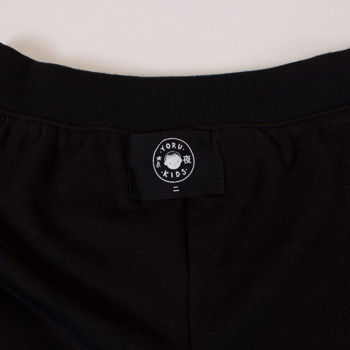 Detalle de la etiqueta Yoru Kids por fuera en la pretina del Short Dinosaurio